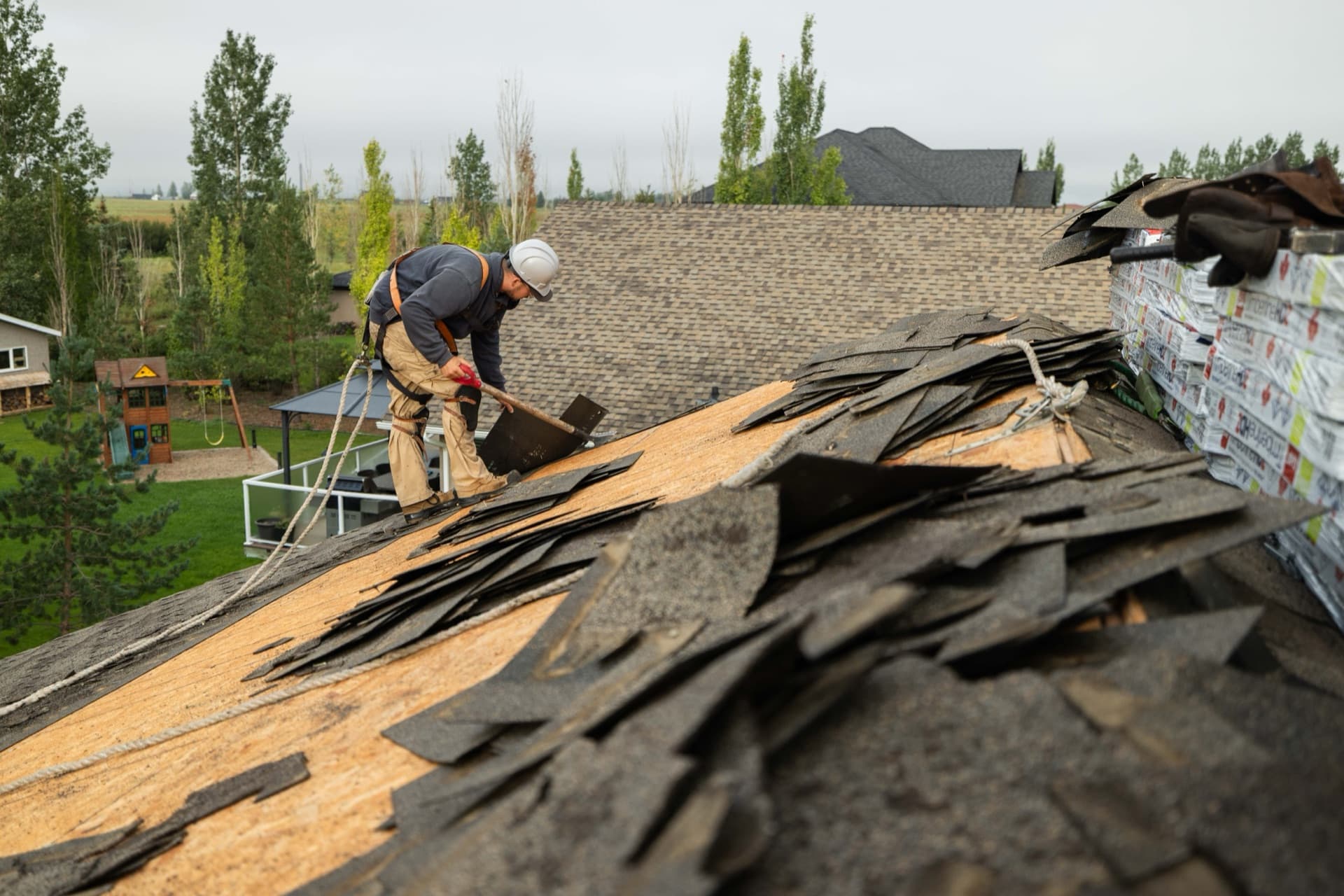 Roofer removing old shingles during tear-off